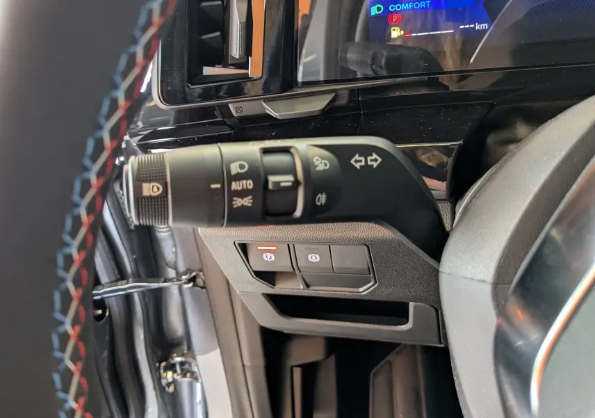 Gros plan sur la commande des clignotants et phares dans l'habitacle gris du Renault Austral e-tech hybride 2025.