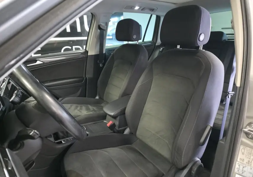 Vue intérieure côté conducteur du Volkswagen Tiguan 2020, sièges avant en microfleece gris foncé avec accoudoir central.