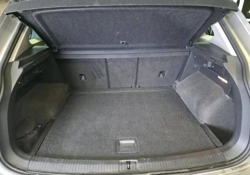 Coffre ouvert du Volkswagen Tiguan gris 2020, montrant un plancher modulable et un espace de rangement spacieux.
