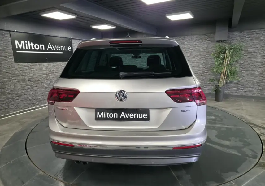 Vue arrière d'un Volkswagen Tiguan gris métallisé 2020 avec feux LED et logo VW bien visibles dans un showroom.