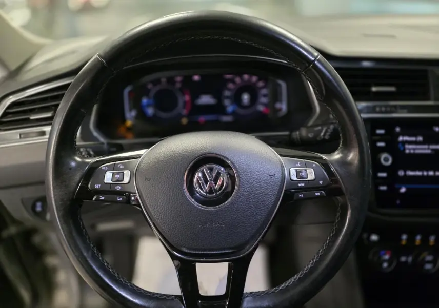 Volant cuir noir Volkswagen Tiguan 2020 vu de face avec commandes multifonctions et tableau de bord digital flou.