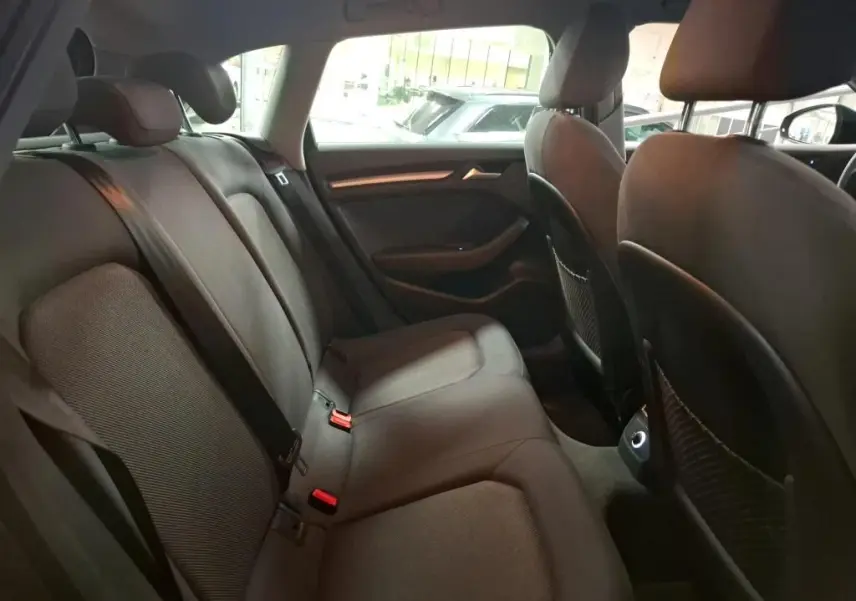 Vue intérieure côté droit de la banquette arrière noire de l'Audi A3 Sportback 2017 avec appuie-têtes et ceintures visibles.