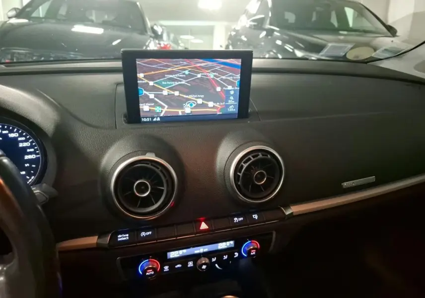 Vue intérieure du tableau de bord noir d'Audi A3 Sportback 2017 avec écran GPS central et aérateurs ronds chromés.