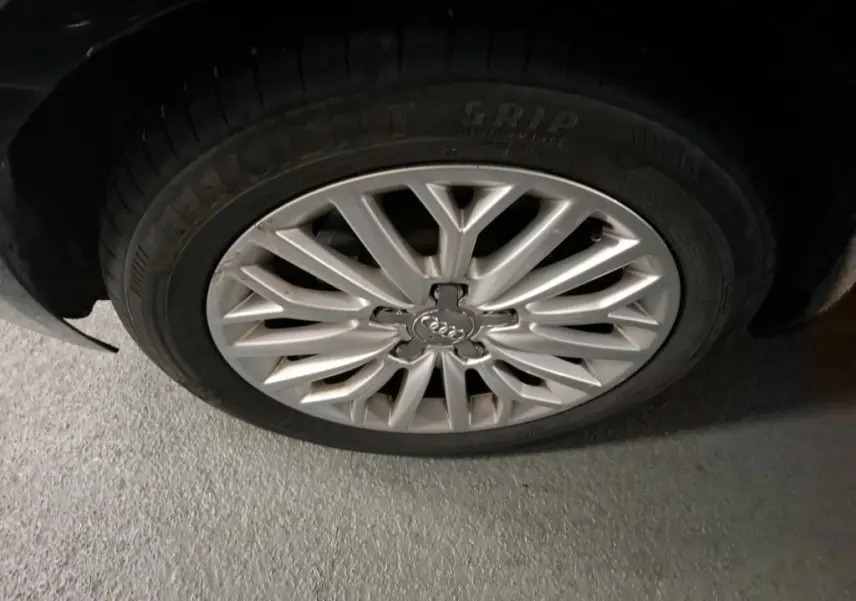 Gros plan sur la jante en aluminium 10 branches argentée de l'Audi A3 Sportback noire, vue côté roue avant.