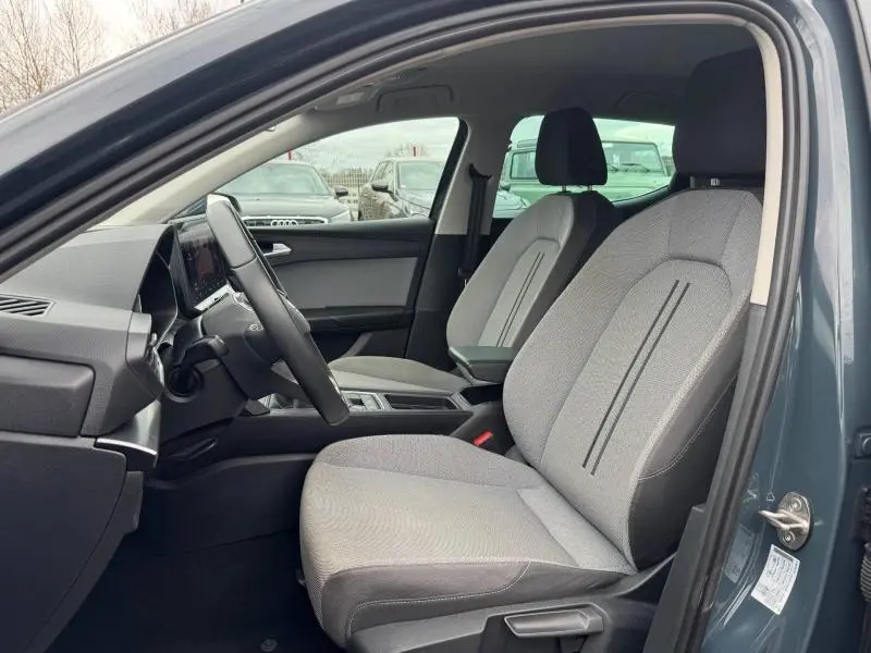 Vue intérieure côté conducteur de la SEAT LEON 2025 gris Graphène, sièges tissu Bleu Fjord et tableau de bord moderne.
