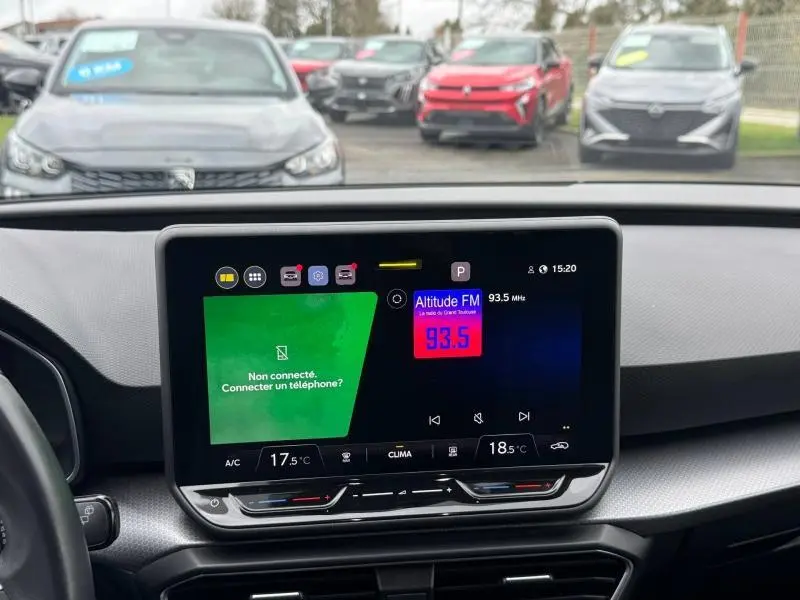 Vue intérieure centrée sur l'écran tactile du tableau de bord du SEAT LEON gris Graphène, avec affichage radio et climatisation.