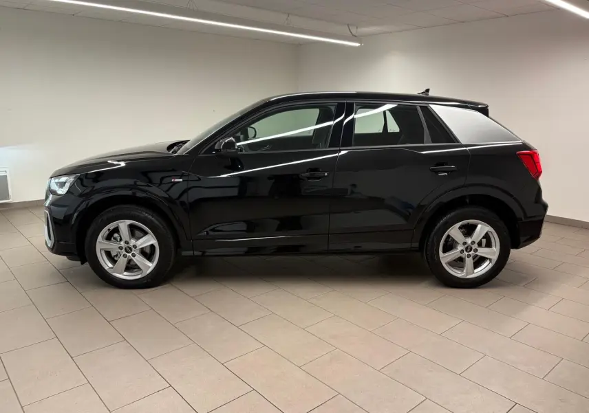 Audi Q2 35 TFSI S Line noir mythic vue de profil côté gauche dans un intérieur neutre, jantes alliage visibles.