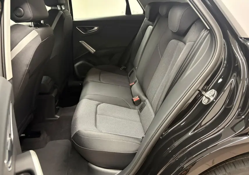 Vue intérieure côté droit des sièges arrière en tissu gris et noir d'un Audi Q2 Noir Mythic 2026, porte ouverte.