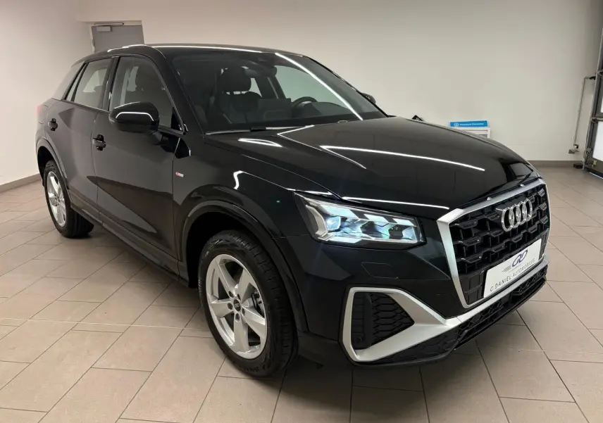 Audi Q2 35 TFSI S line noir mythic en 3/4 avant droit, mettant en valeur ses phares LED et sa calandre distinctive.