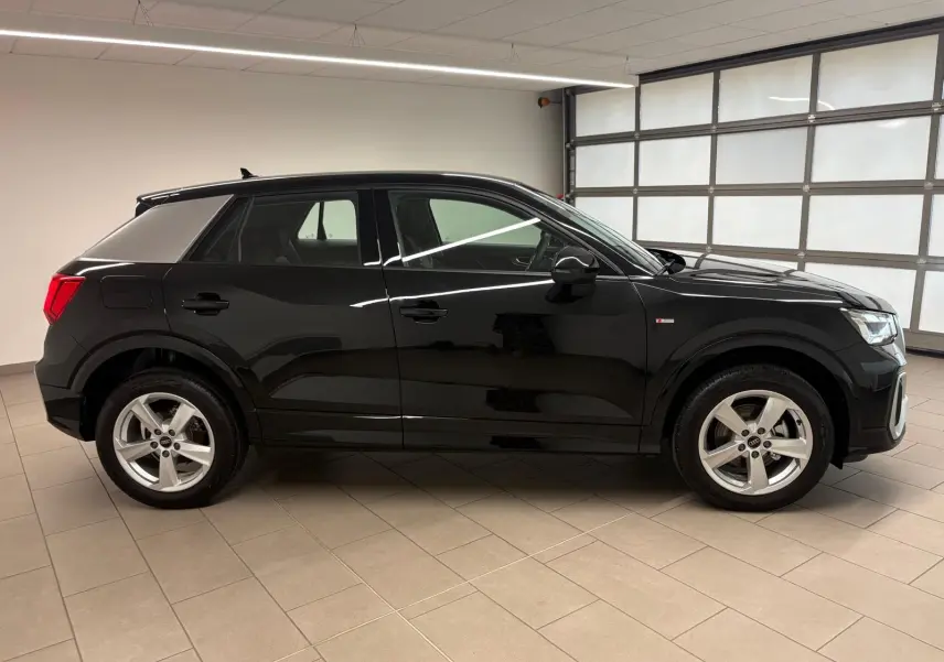 Audi Q2 35 TFSI S Line noir mythic vue de profil côté gauche dans un garage lumineux.