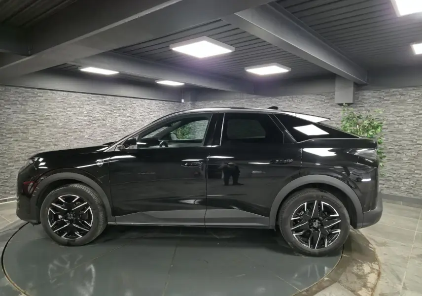 Peugeot 3008 noir en profil droit dans un intérieur, avec jantes alliage noires et détails noirs mats.
