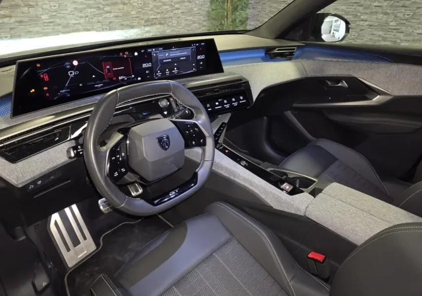 Intérieur du Peugeot 3008 GT 2025 vu côté conducteur, tableau de bord numérique et sellerie gris/noir moderne.