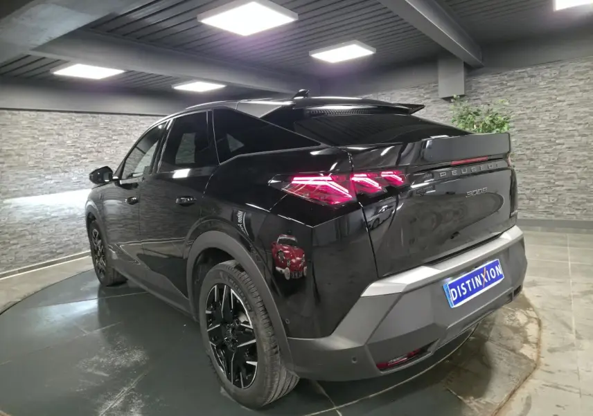 Peugeot 3008 noir vue 3/4 arrière droit en intérieur, feux arrière LED et jantes alliage noires visibles.