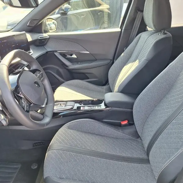 Vue intérieure côté conducteur du Peugeot 2008 Hybrid 136 Allure 2025, sièges gris et cockpit numérique visible.