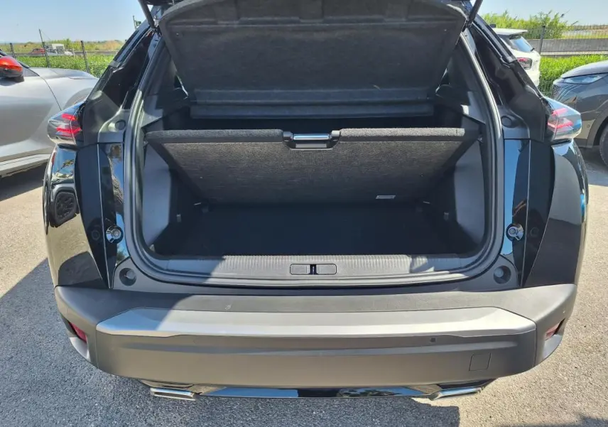 Vue arrière du coffre ouvert d’un Peugeot 2008 Hybrid 136 noir, avec barres de toit visibles sur le dessus.