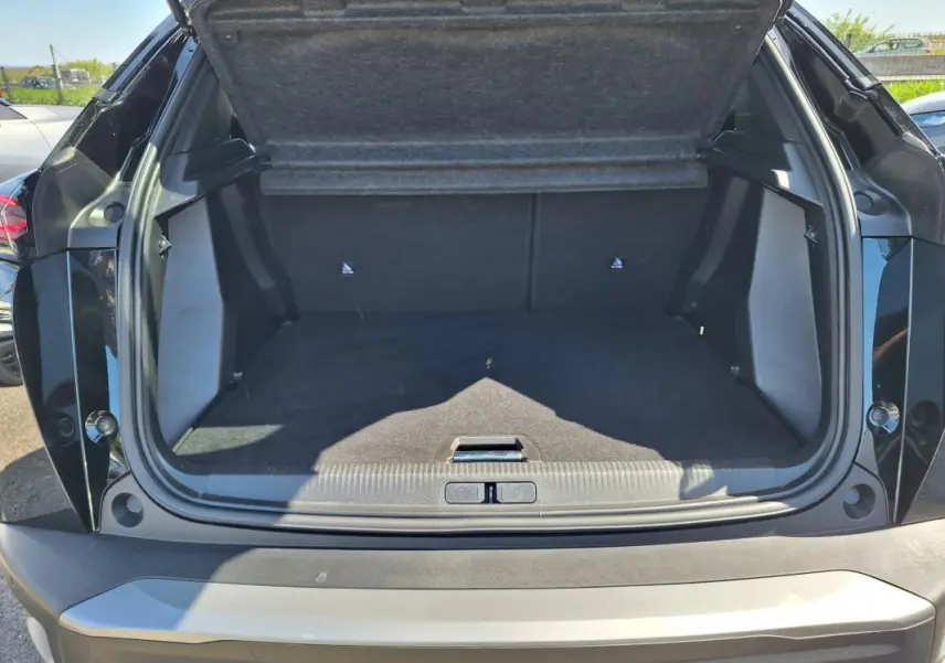 Coffre ouvert vu de l'arrière d'un Peugeot 2008 noir, montrant l'espace de chargement vide et la garniture intérieure.