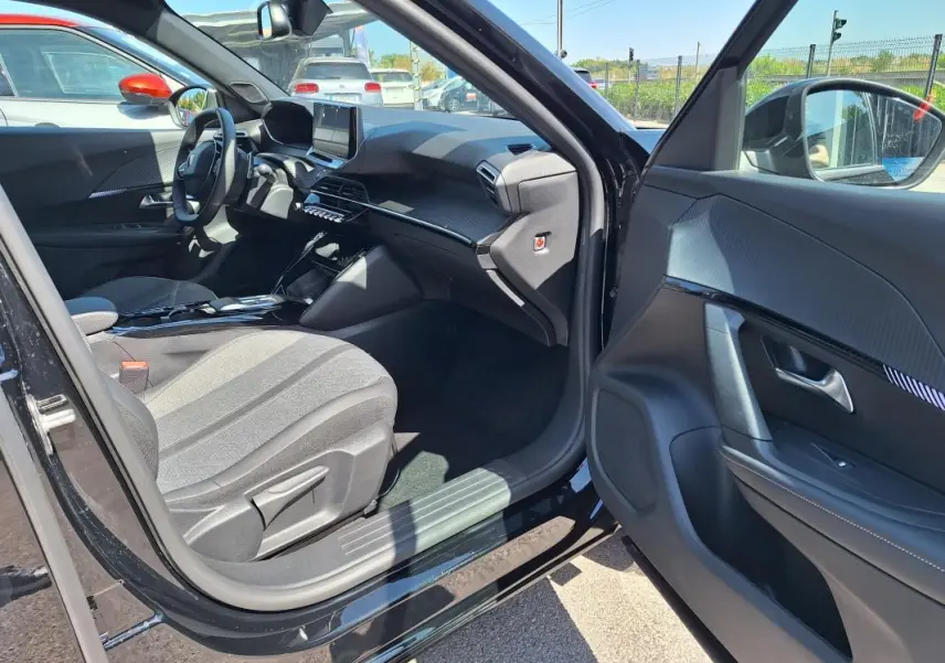 Vue intérieure côté conducteur d’un Peugeot 2008 Hybrid noir, montrant le tableau de bord moderne et l’écran tactile.
