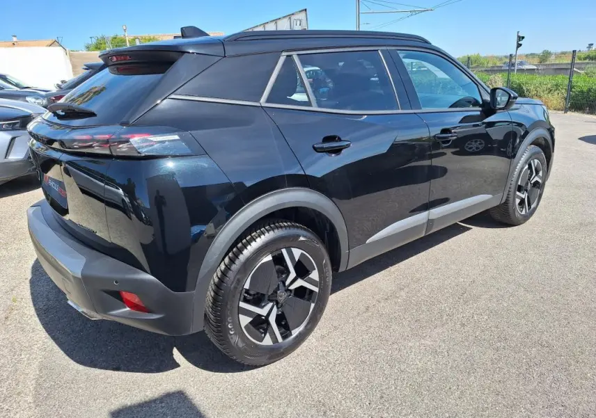 Vue 3/4 arrière droite d’un Peugeot 2008 Hybrid noir avec barres de toit et jantes alliage 17 pouces.