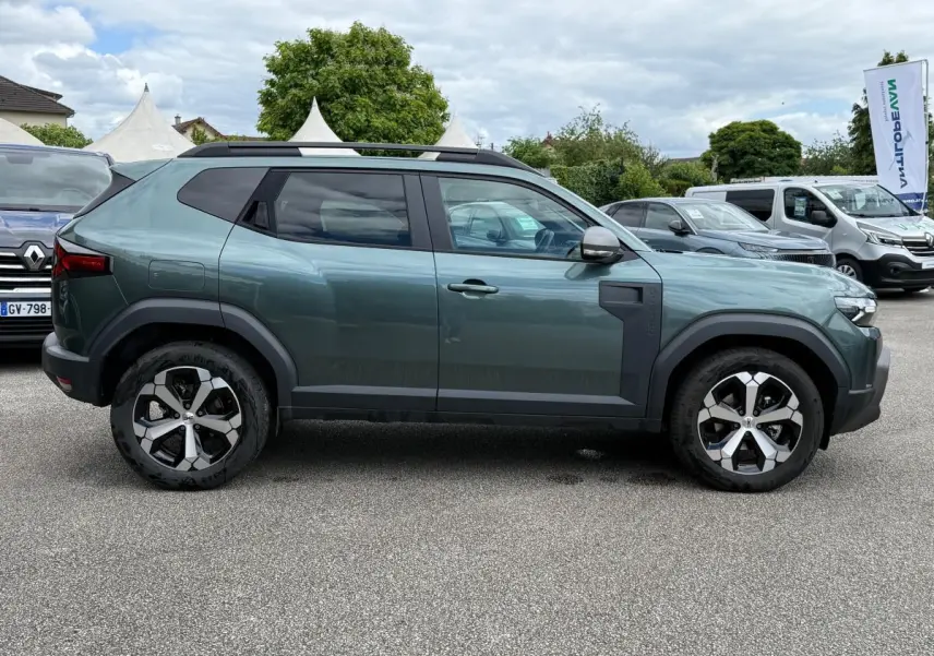 Vue de profil côté gauche d'un Dacia Duster Hybrid 140 Journey vert cèdre avec jantes alliage et barres de toit noires.