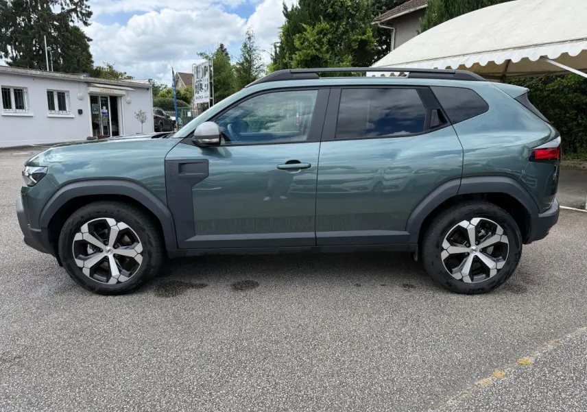 Vue de profil côté gauche du Dacia Duster Hybrid 140 Journey vert cèdre avec jantes alliage et barres de toit noires.