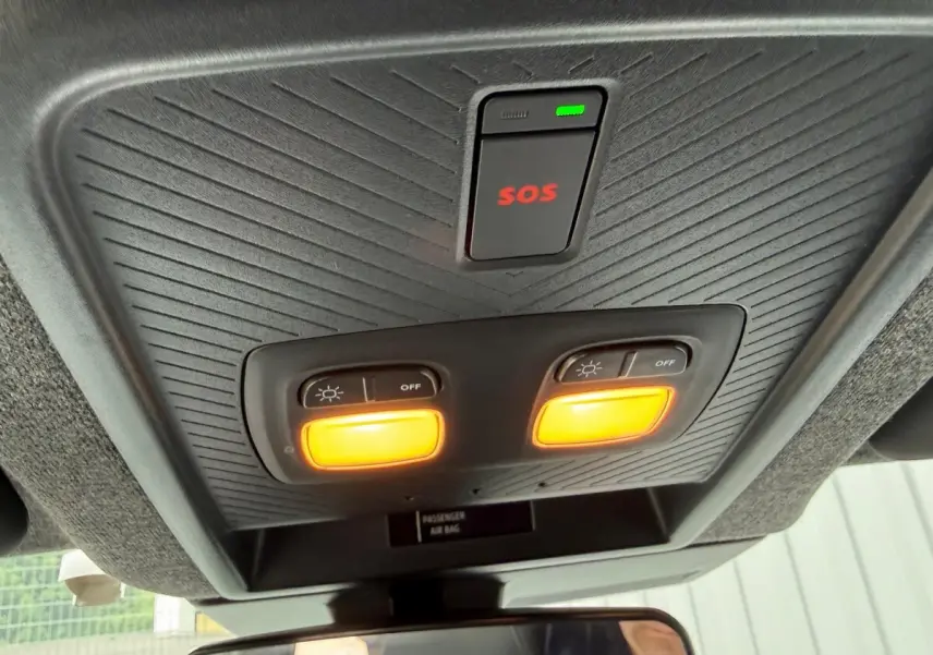 Vue intérieure du plafonnier avec éclairage orange et bouton SOS du Dacia Duster Hybrid 140 Journey 2025.
