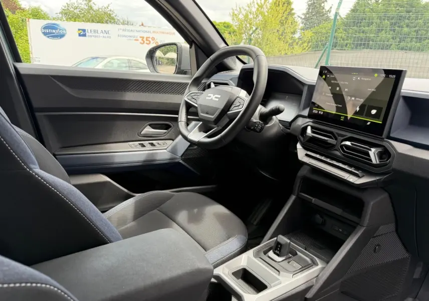 Intérieur du Dacia Duster Hybrid 140 Journey 2025 vu côté conducteur, avec écran tactile central et volant multifonctions.