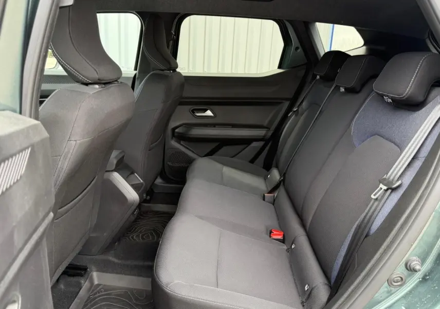 Vue intérieure côté droit sur la banquette arrière noire du Dacia Duster Hybrid 140 Journey vert cèdre 2025.