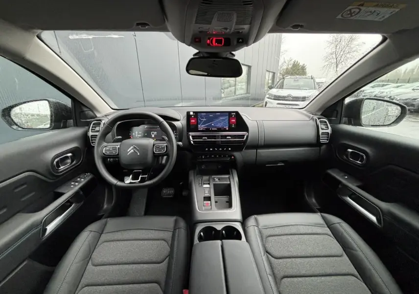 Vue intérieure frontale du Citroën C5 Aircross 2025, tableau de bord noir avec écran tactile et volant multifonction.
