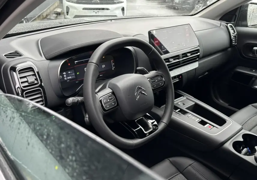 Vue intérieure côté conducteur du tableau de bord noir et volant cuir du Citroën C5 Aircross 2025.
