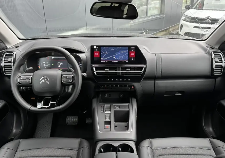 Vue intérieure avant du Citroën C5 Aircross 2025, tableau de bord noir avec écran tactile central et volant multifonction.