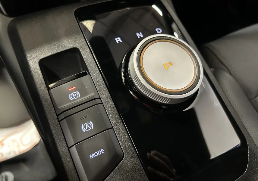 Gros plan sur la molette de sélection de vitesse et les boutons de contrôle du mode de conduite dans l’habitacle du MG3 Pebble Black.