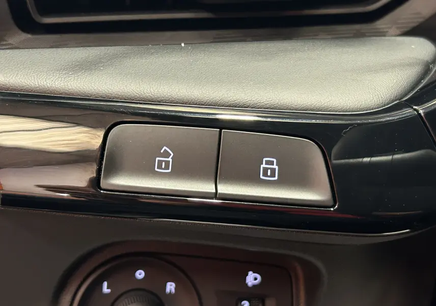 Gros plan sur les boutons de verrouillage centralisé et réglage des rétroviseurs intérieurs noirs du MG3 Pebble Black 2026.