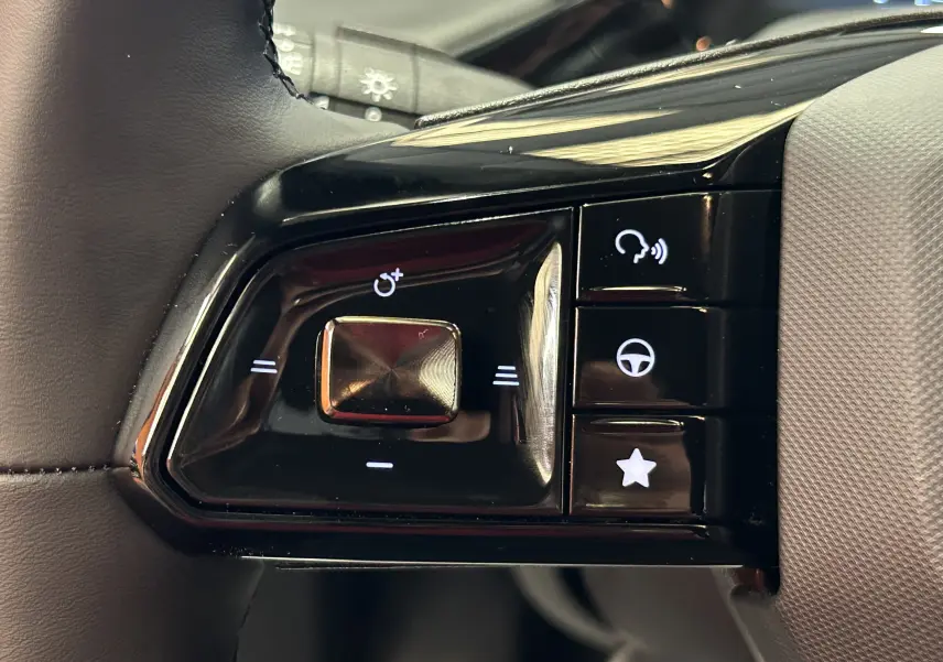 Gros plan sur les commandes noires au volant du MG3 1.5 Hybrid+ 195 Luxury Pebble Black, boutons lumineux blancs.