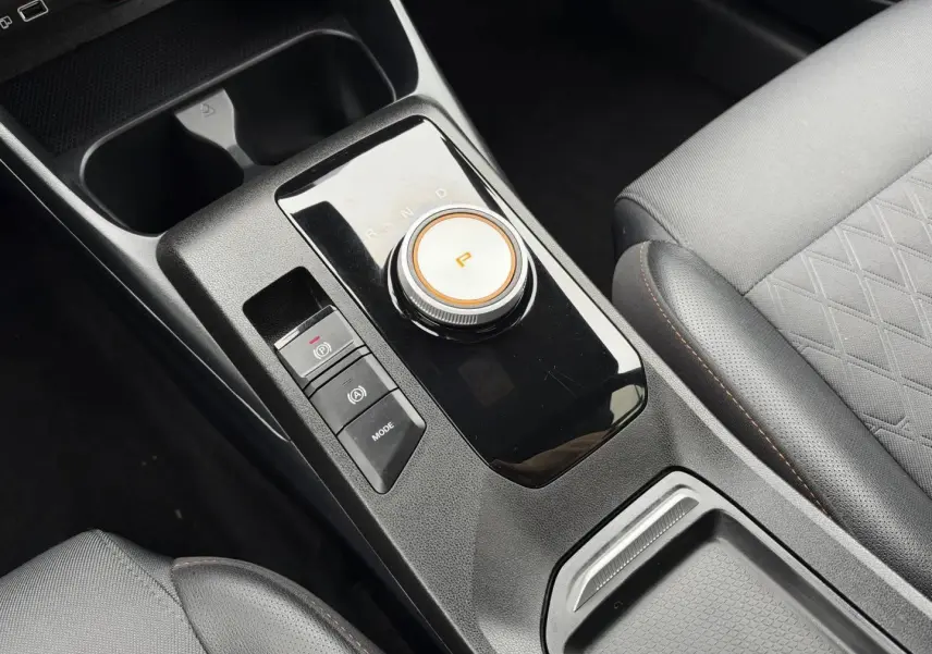 Gros plan sur la console centrale noire et le levier rotatif de boîte auto dans l’habitacle gris du MG3 1.5 Hybrid+ 2025.