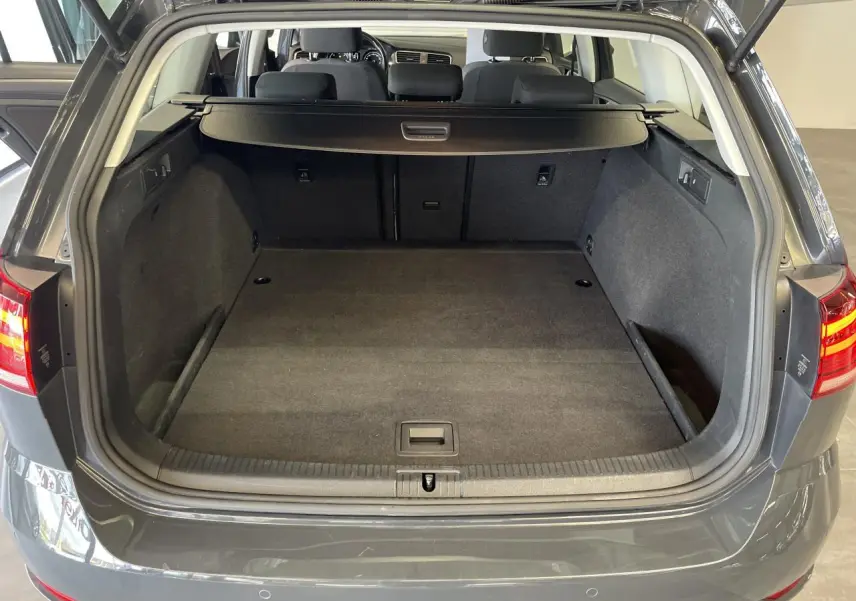 Coffre ouvert d'une Volkswagen Golf SW 1.6 TDI gris foncé, vue arrière montrant l'espace de chargement vide.