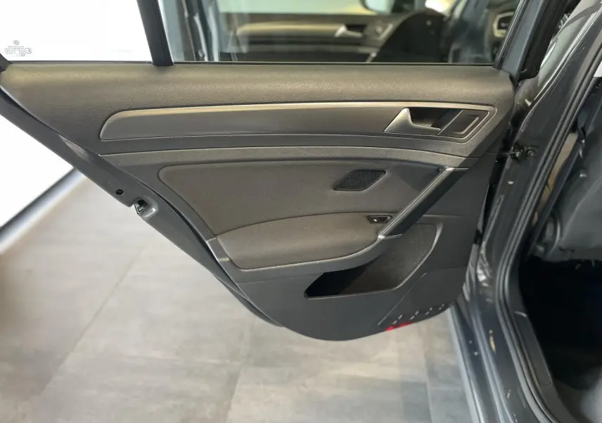Porte arrière droite ouverte d'une Volkswagen Golf SW gris foncé, montrant le revêtement intérieur noir avec insert décoratif chromé.