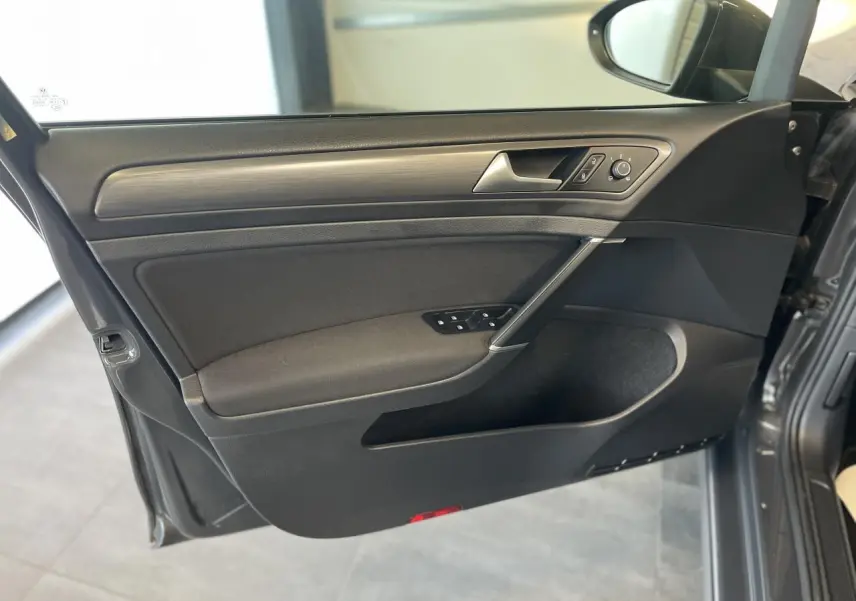 Intérieur côté gauche de la porte avant d'une Volkswagen Golf SW gris foncé, avec commandes électriques et insert décoratif.