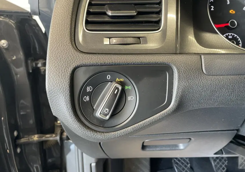Vue rapprochée du tableau de bord côté gauche d'une Volkswagen Golf gris foncé, avec commande des phares en mode auto.