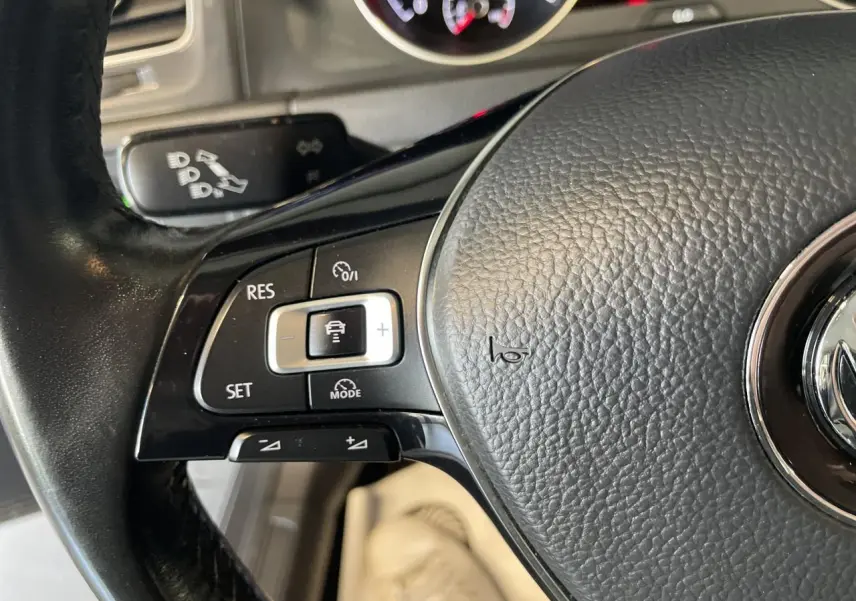 Gros plan sur le volant cuir noir de la Volkswagen Golf SW 2017, avec commandes de régulateur de vitesse visibles.