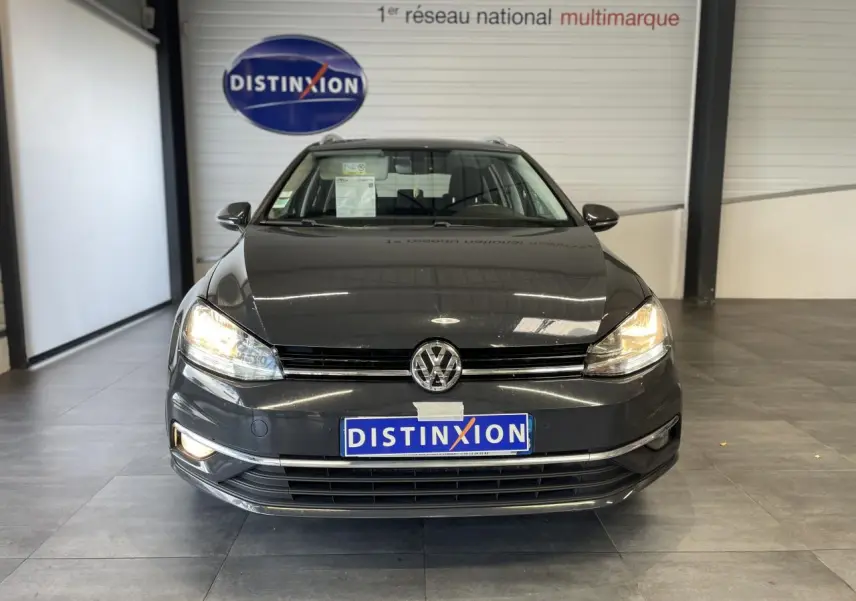 Volkswagen Golf SW gris foncé vue de face avec phares allumés en intérieur showroom Distinxion.