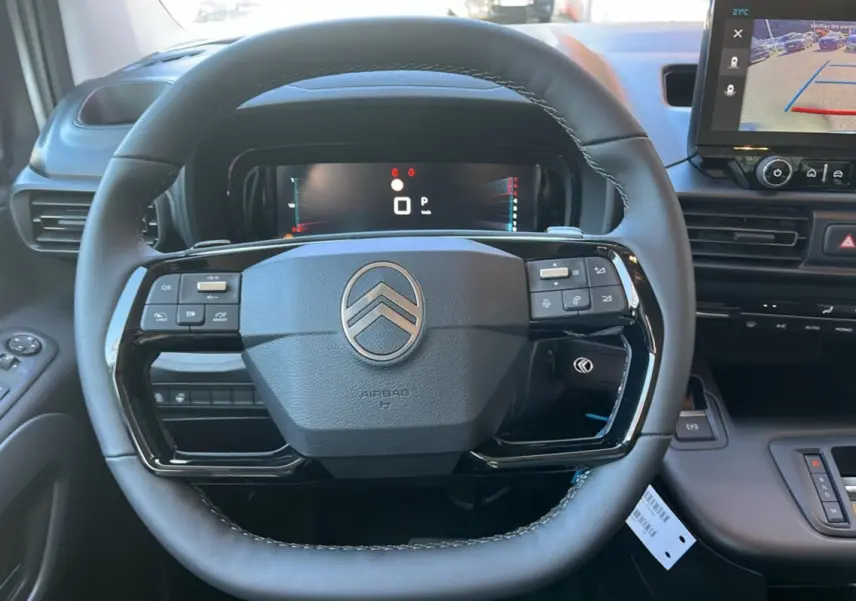 Vue rapprochée du volant cuir multifonctions noir du Citroën Berlingo 2026 avec tableau de bord digital et écran central tactile.