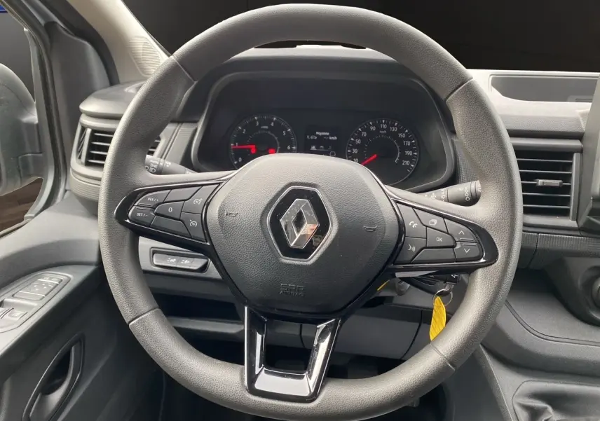Vue intérieure centrée sur le volant noir du Renault Trafic Combi 2023 avec commandes intégrées et tableau de bord visible.