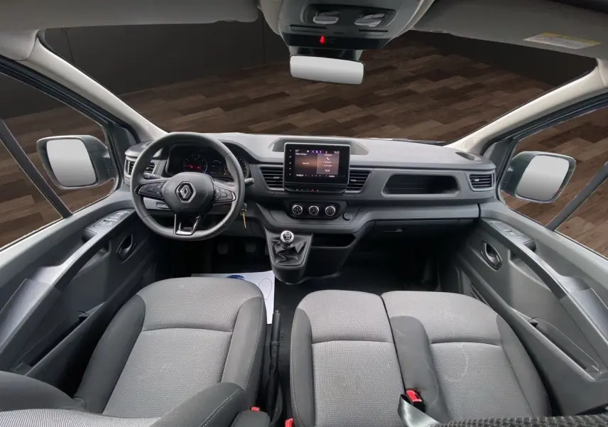 Vue intérieure avant du Renault Trafic Combi 2023 gris platine, montrant le tableau de bord avec écran tactile et volant multifonction.