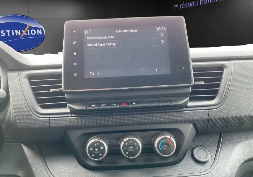 Vue rapprochée du tableau de bord du Renault Trafic Combi gris platine 2023, avec écran tactile et commandes de climatisation.