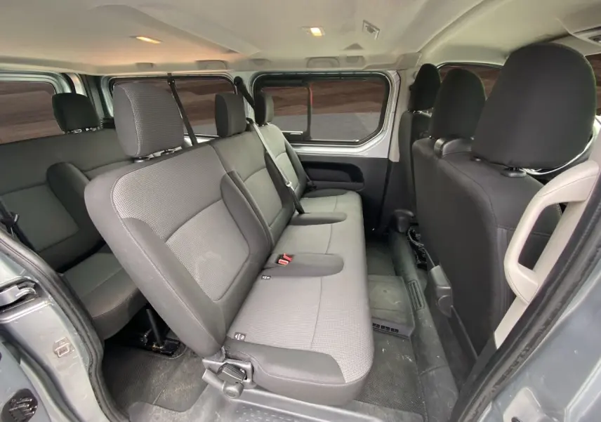 Vue intérieure côté droit sur la banquette arrière en tissu gris du Renault Trafic Combi L2 9 places, finition 2023.