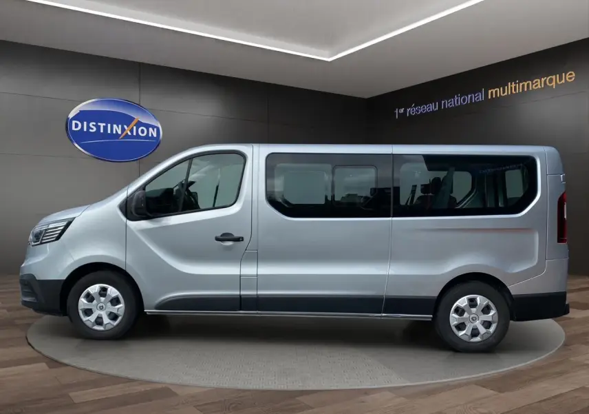 Profil côté gauche d’un Renault Trafic Combi gris platine 2023, version 9 places, dans un showroom intérieur.