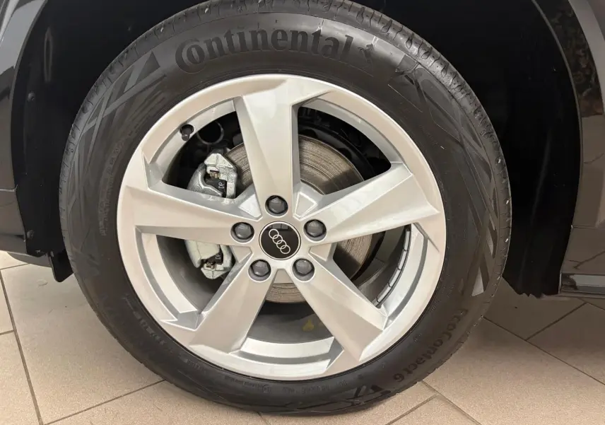 Gros plan sur la roue avant gauche d’un Audi Q2 Noir Mythic avec jante alliage argentée et pneu Continental.