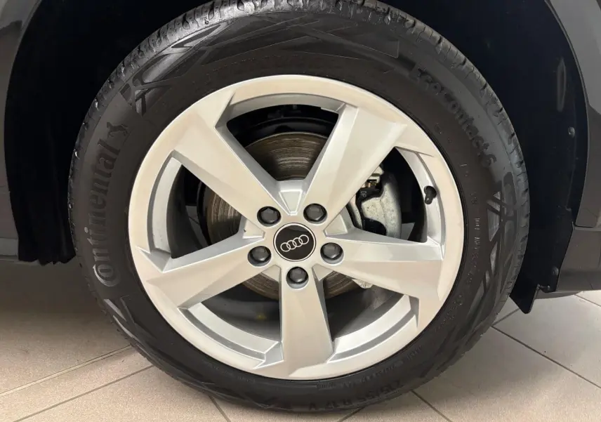 Gros plan sur la roue avant droite d’un Audi Q2 Noir Mythic avec jante alliage argentée cinq branches.