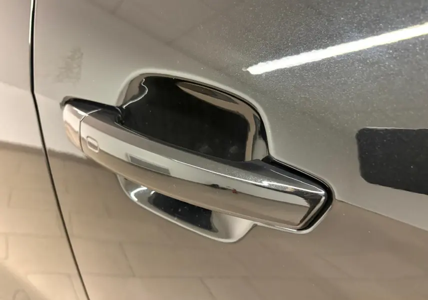 Poignée de porte chromée sur la porte avant gauche d’un Audi Q2 35 TFSI 150 S tronic 7 S line noir mythic.