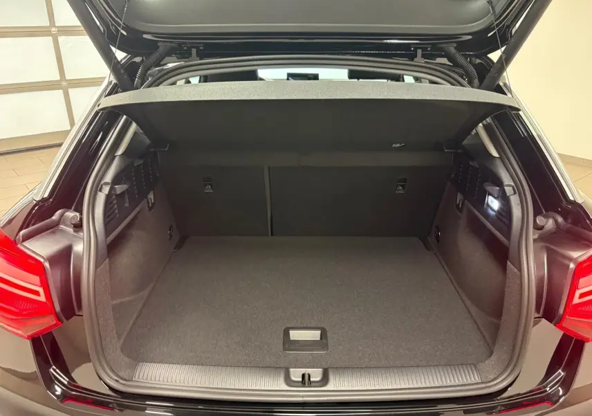 Coffre ouvert vu de l'arrière d'un Audi Q2 Noir Mythic, montrant l'espace de chargement et le hayon électrique.